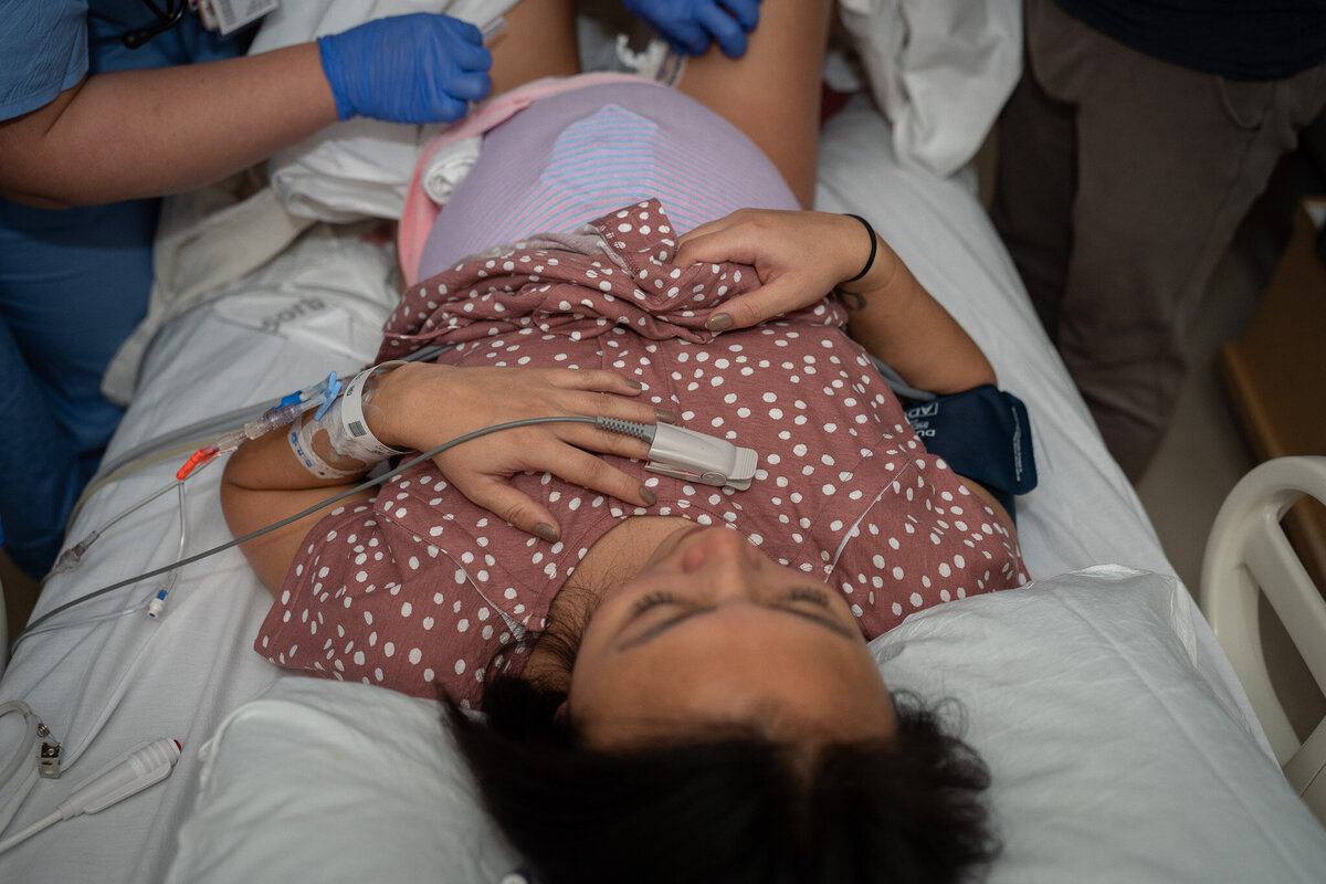 a pregnant person is laying on a hospital bed about to give birth in Seattle, WA.