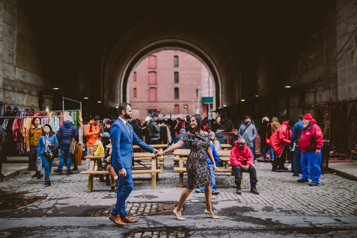 A couple walking past the archway in dumbo brooklyn 