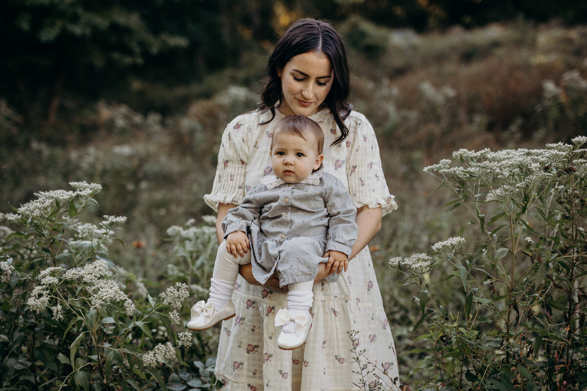 mother holding her baby in a field of wildflowers