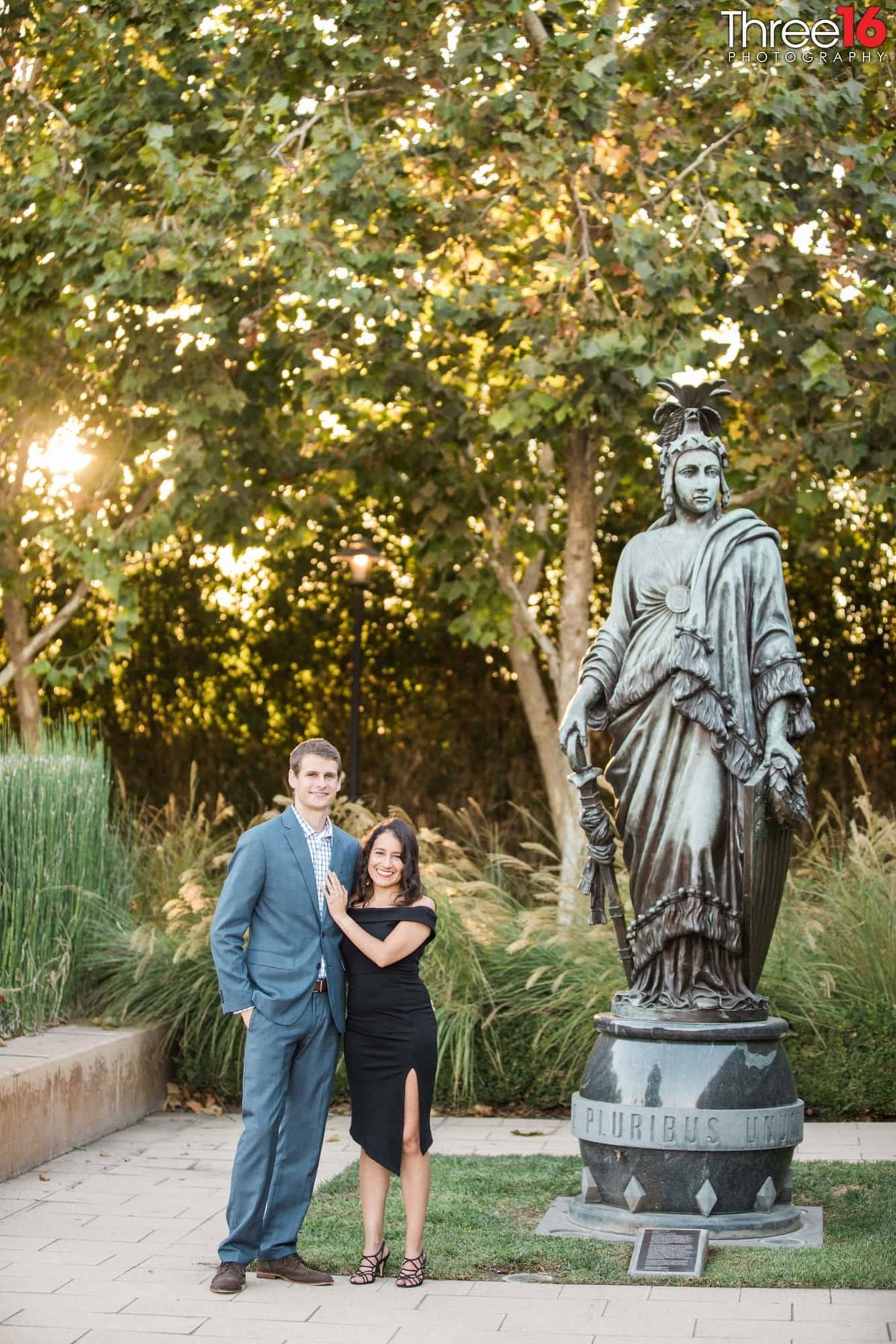Engaged couple pose next to a statue at Sculpture Garden