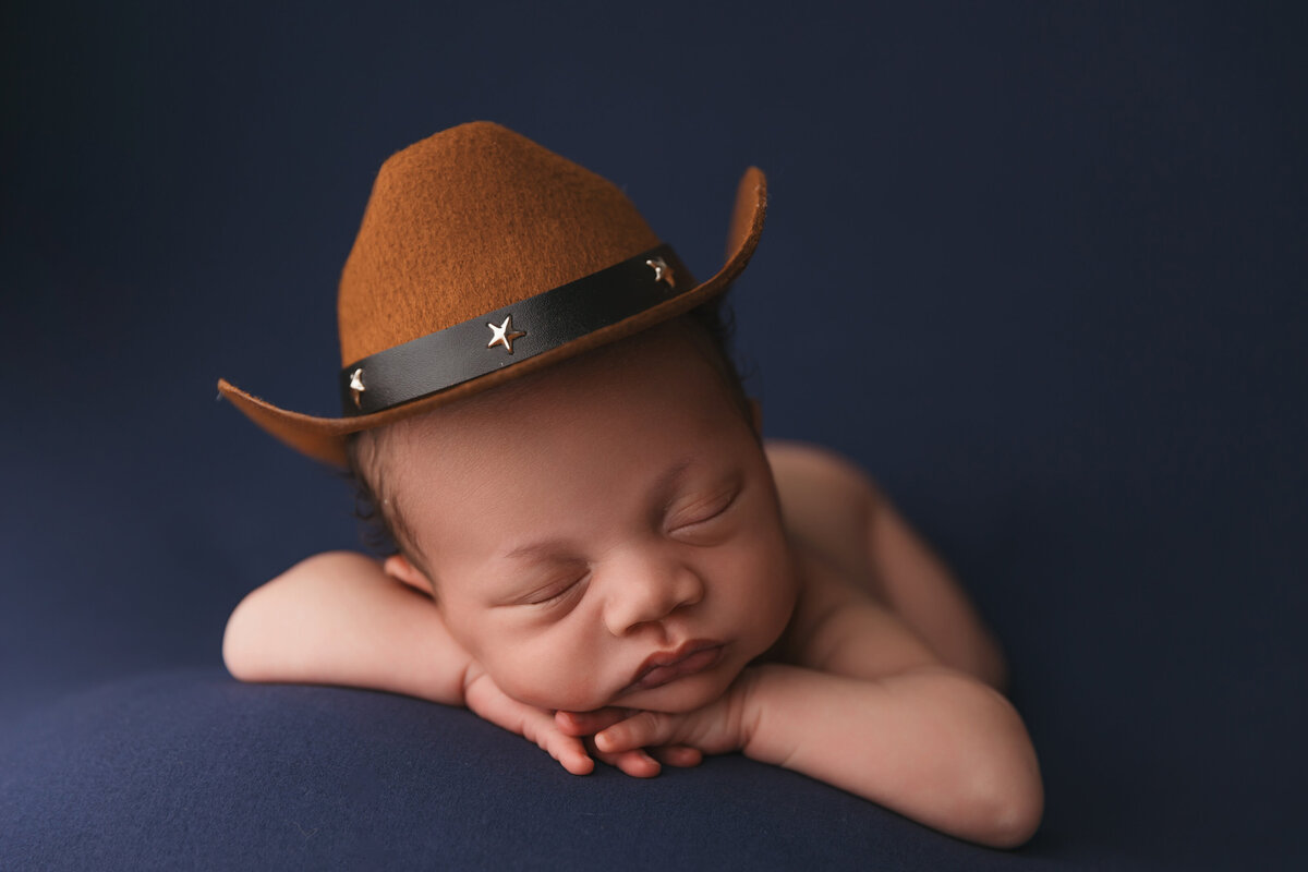 Baby posing for Phoenix newborn session on blue bacldrop