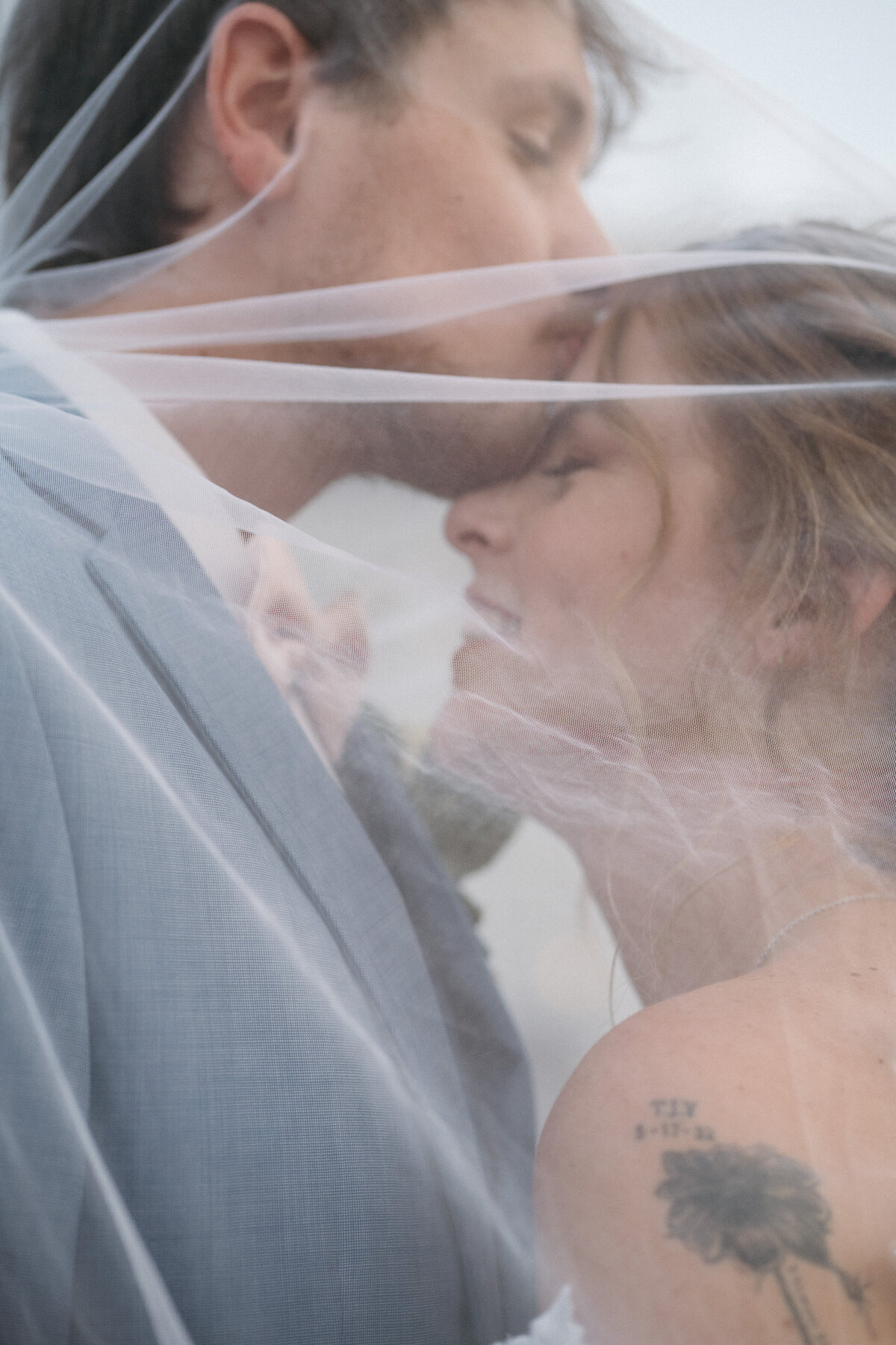 Man and woman embrace under wedding veil