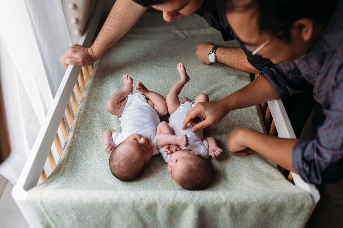Newborn Photographer, a dad admires twin babies on the changing table