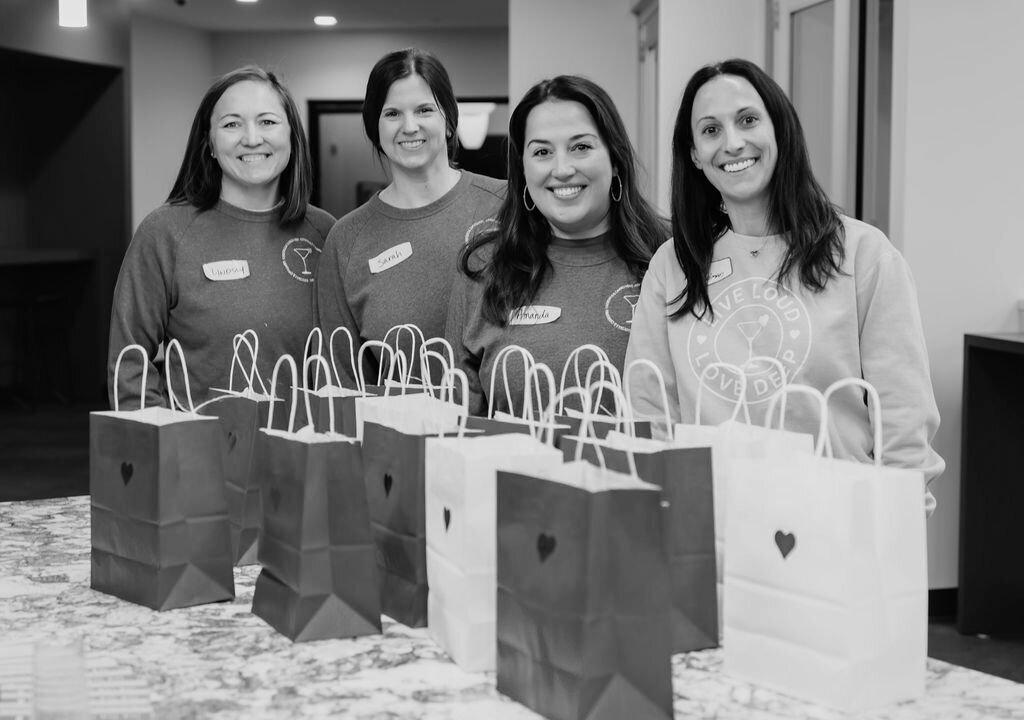 Women gather around gift bags at self care event.