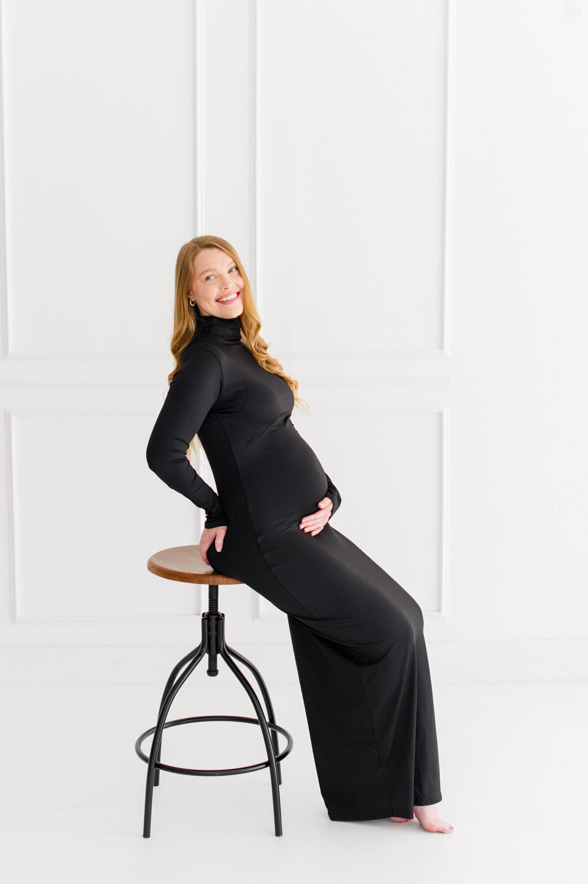 Orlando Maternity photographer captures pregnant mom sitting on a stool with her hand on her belly
