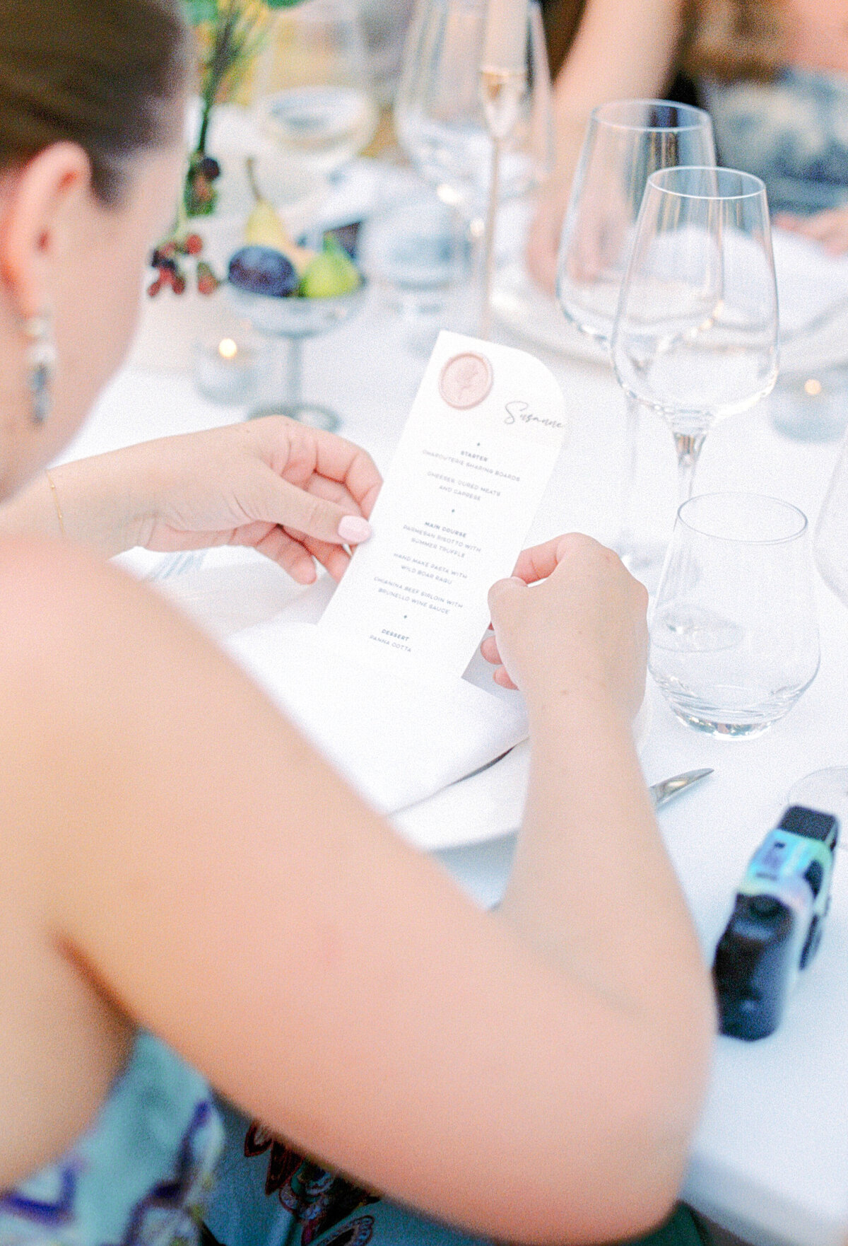 Film photograph of guests looking at their wedding reception dinner menu photographed by Italy wedding photographer at Villa Montanare Tuscany wedding