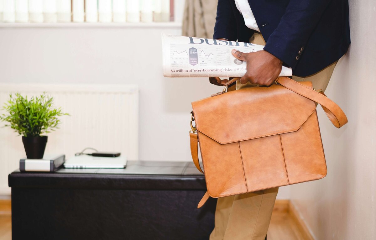 Photo of an African American man with briefcase and newspaper in hand ready for work 