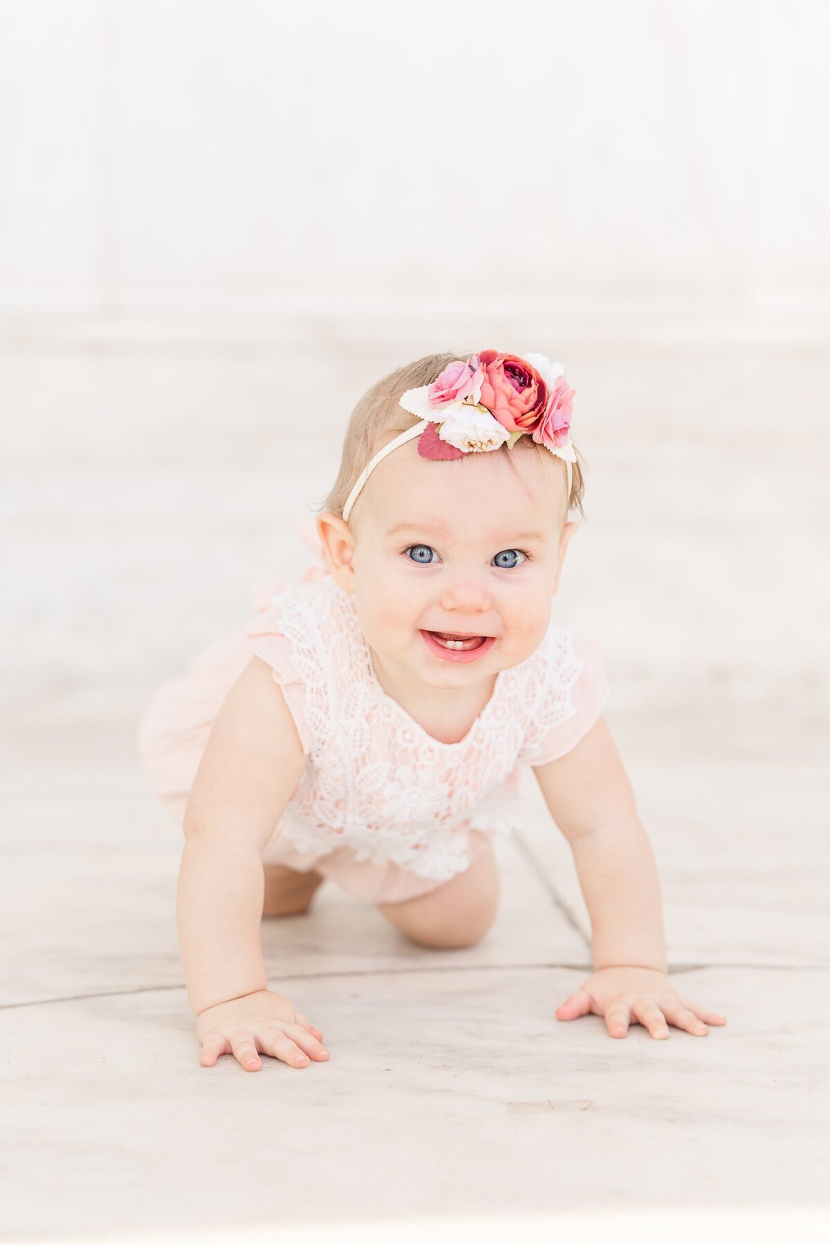 Toddler girl crawling on a white marble backdrop