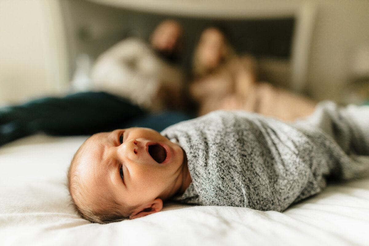 newborn baby swaddled on bed yawning by harrisburg pa newborn photographer