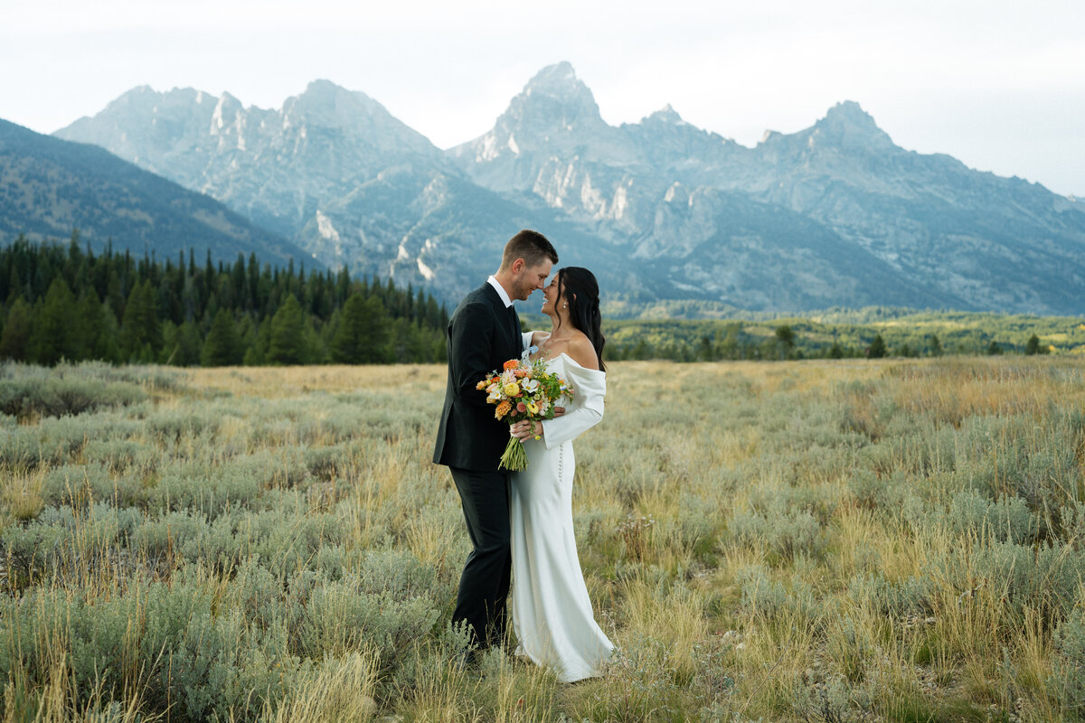 Bridals wedding photography in the Grand Tetons. The bride and groom and looking into each others eyes and smiling with the Tetons behind them.