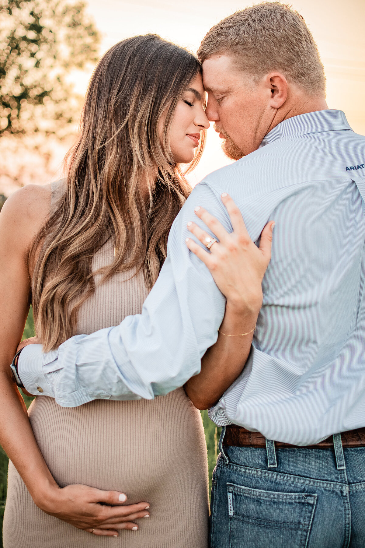 A mom and dad to be touch foreheads and close their eyes as they think about the arrival of their second child.