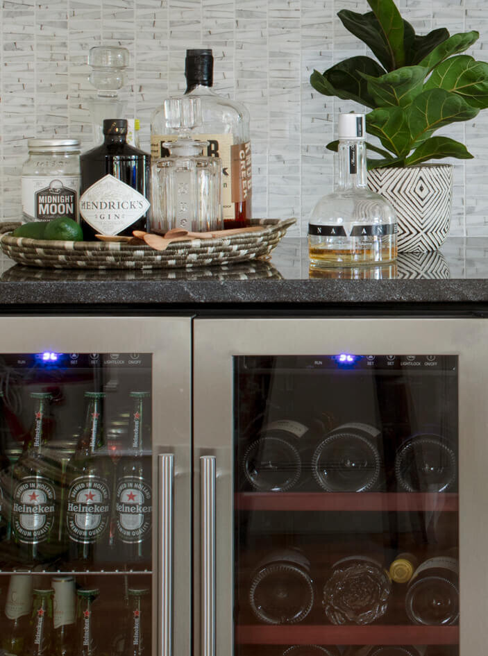 Kitchen designers in Westwood create a home with dark grey counters, Ann Sacks backsplash tile, and an under-counter beverage refrigerator for convenience.