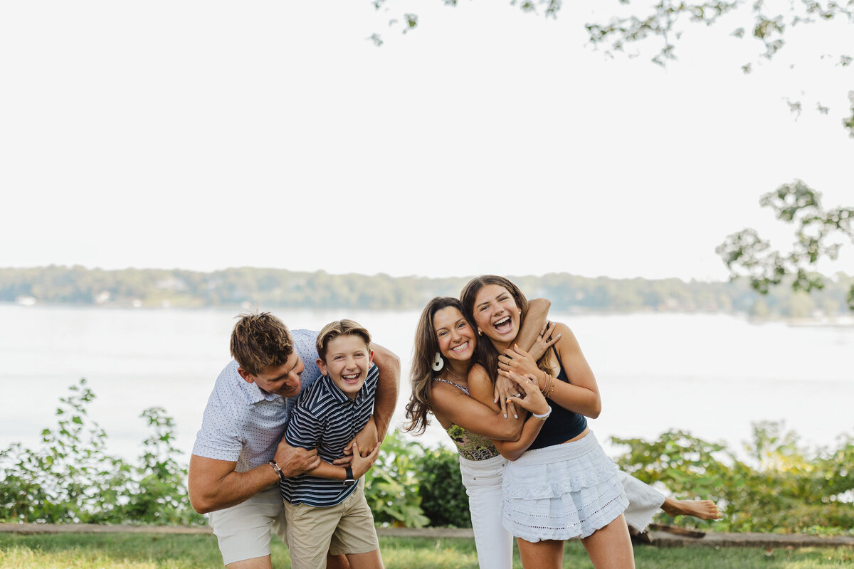 A family of four laughs while hugging.