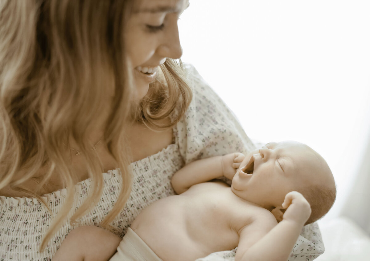 mother holding newborn while it yawns