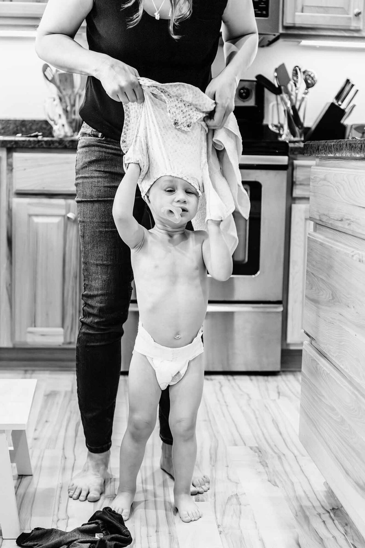 Mother dressing toddler girl at home, Stevensville, Montana