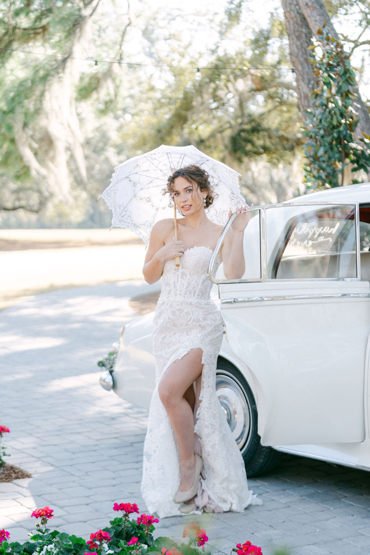 bride with a parasol next to a vintage Rolls Royce at Hewitt Oaks wedding venue in Bluffton South Carolina captured by Savannah wedding photographer Magnolia West Photography