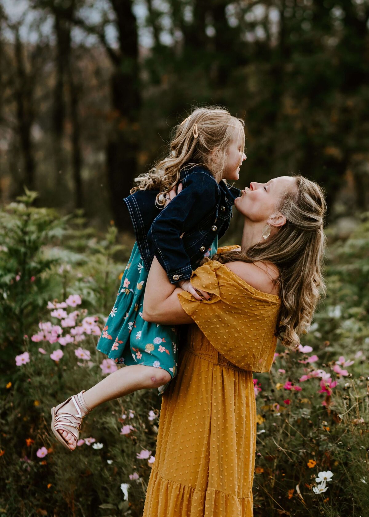 A mother gently holds her daughter amidst a field of flowers, captured by a Pittsburgh family photographer.