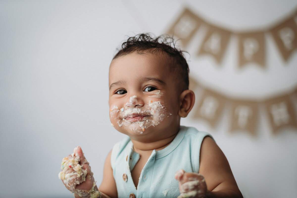 smiling One year old boy covered in cake for a cake smash shoot