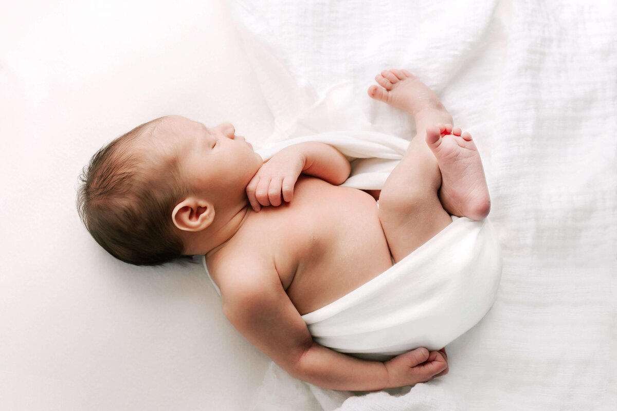 Newborn wrapped up and blacklight on white