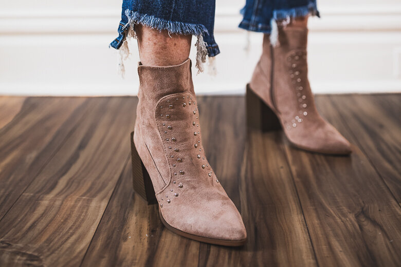 A close-up image of tan/brown suede ankle boots with decorative perforations, shown from ankle down with frayed hem jeans visible above. The boots are photographed on a wooden floor.

Image 9: A group of six professionally dressed people standing in a line outdoors with a city skyline visible in the background. The Pittsburgh skyline can be seen with tall buildings and what appears to be the state capitol dome. The group is wearing business attire in various colors.

Image 10: A close-up of hands holding a decorative blue egg or ornament with an intricate cut-out pattern showing orange/gold underneath. The detailed craftsmanship features flower-like designs carved into the blue exterior.

Image 11: A young woman standing outdoors in an urban setting wearing a plaid or checkered blazer and dark pants. She's positioned near colorful painted steps or a rainbow-colored surface, with buildings visible in the background.

