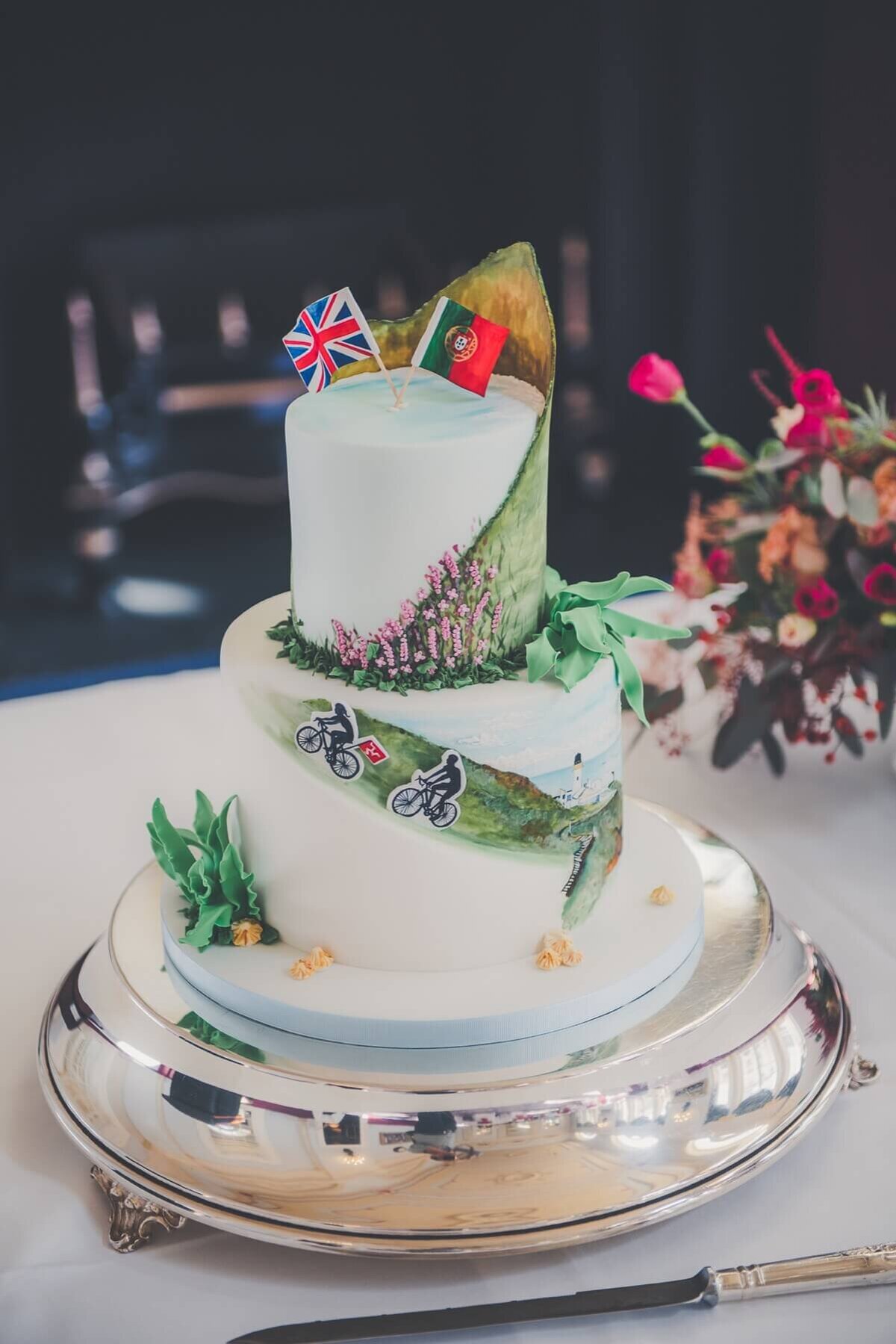 A unique hand painted wedding cake with 2 flags on the top to indicate the bride and grooms country of origin