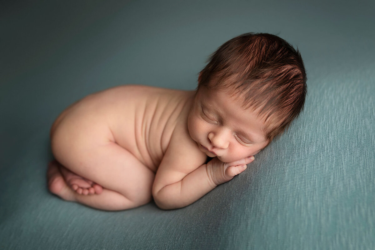 Baby boy posed on blue during his newborn session.