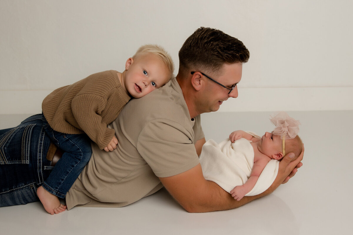 dad on floor holding baby with brother