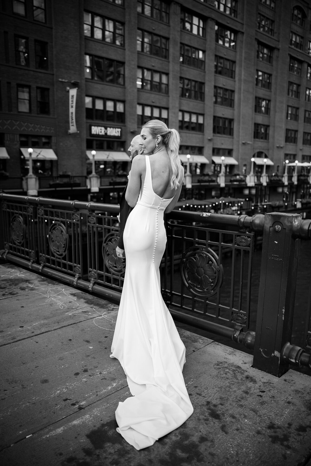 black and white picture of slim and fit bride with groom on Chicago bridge