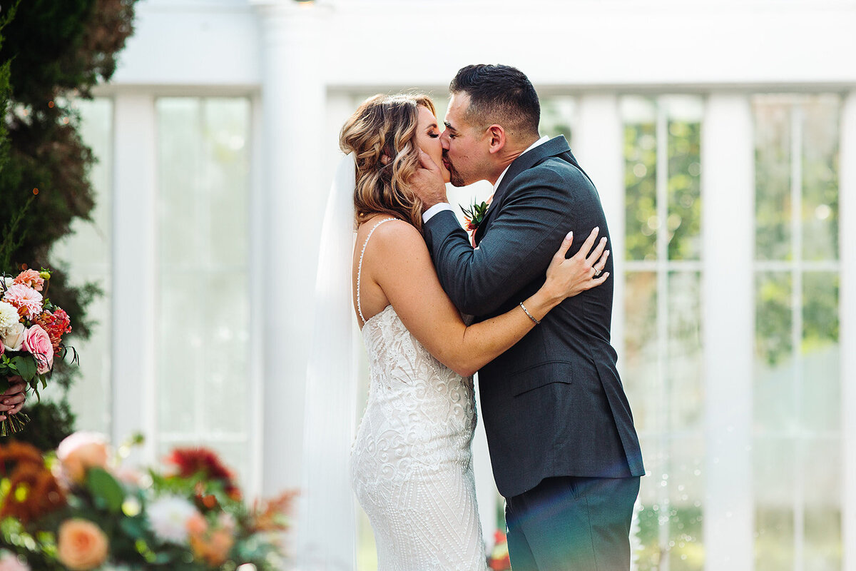 Bride and groom share a first kiss during their wedding ceremony.