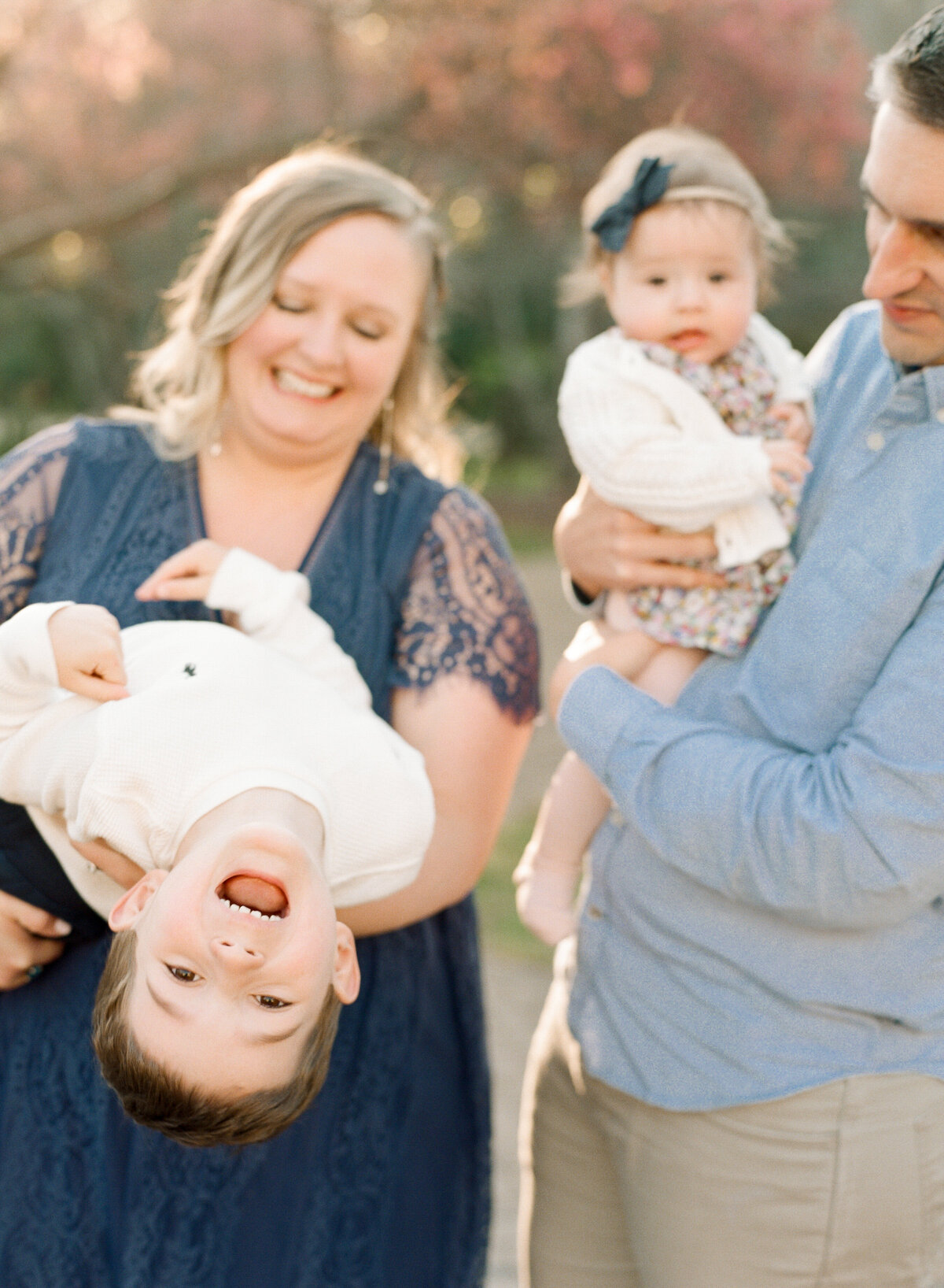 Big brother laughs and hangs upside down during a family session at The Sutherland in Wake Forest.  Image by Raleigh maternity photographer A.J. Dunlap Photography.