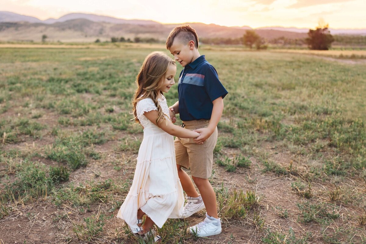 Brother and sister dancing in a field at their family photo session