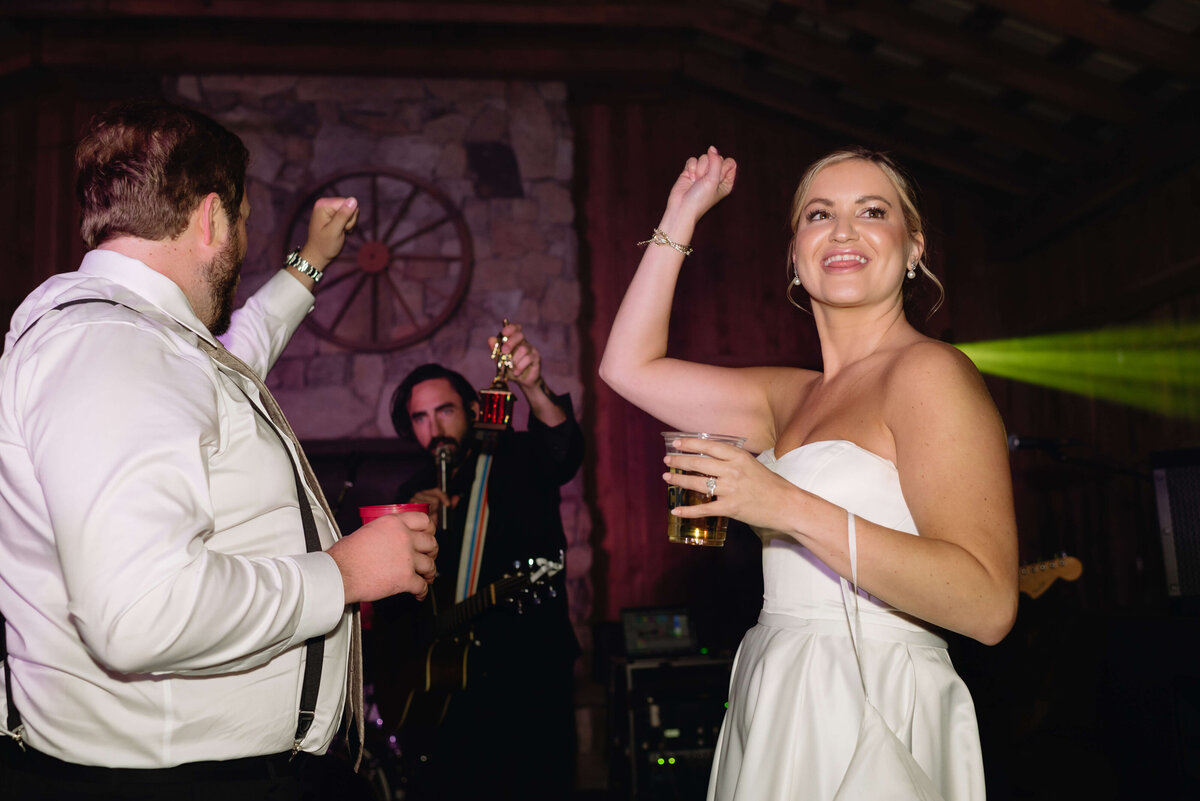 bride and groom dancing with strob lights and cheering with the dj