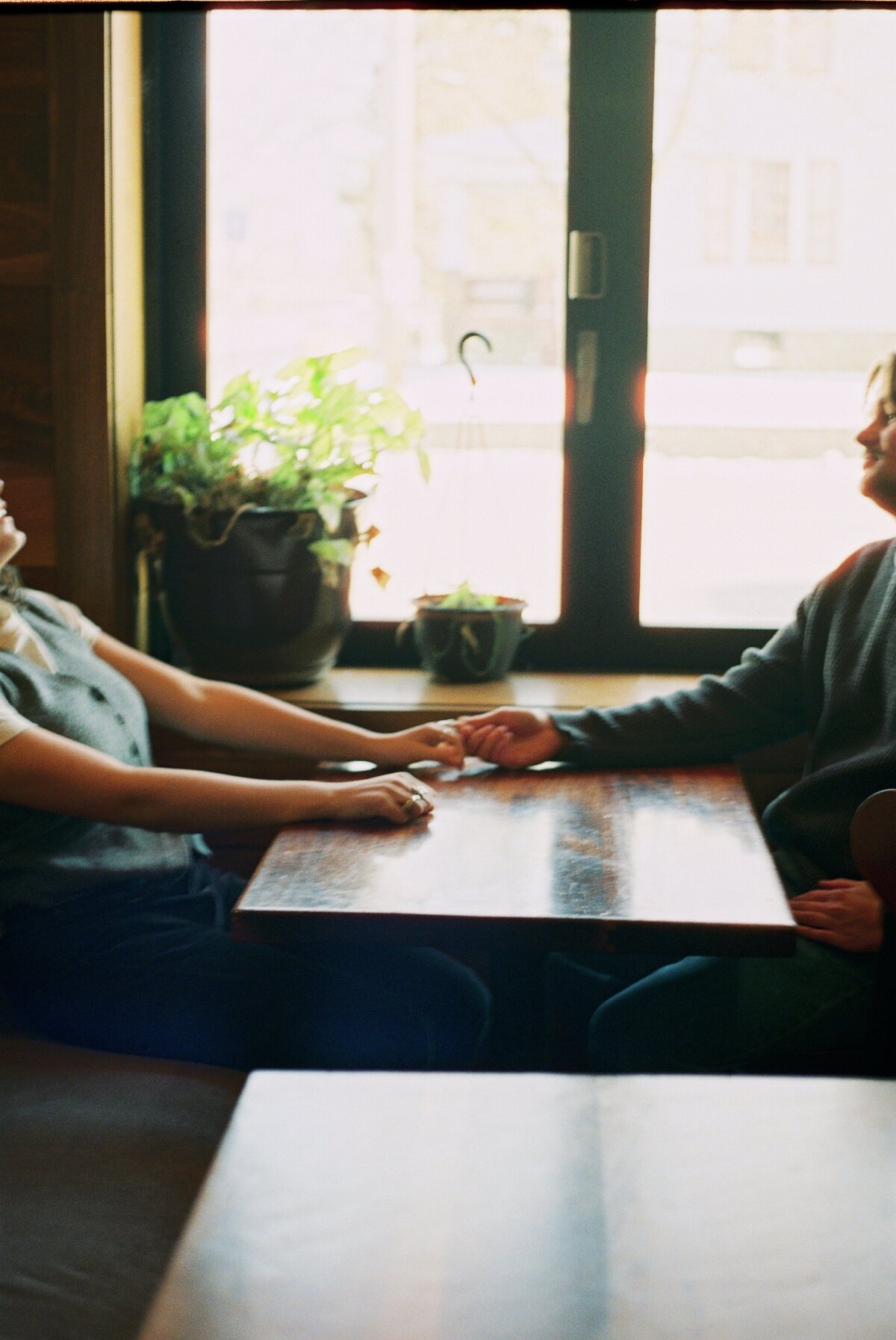 couple holding hands while sitting in cafe, super 8 photography