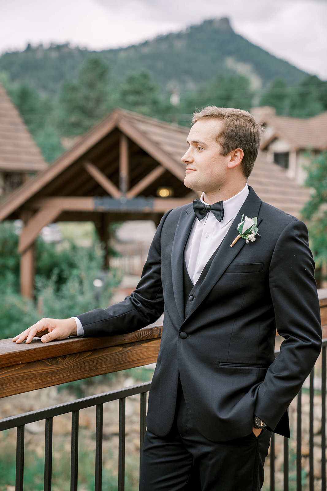 Groom check out the view before his wedding ceremony in a black suit at the Landing at Estes Park.