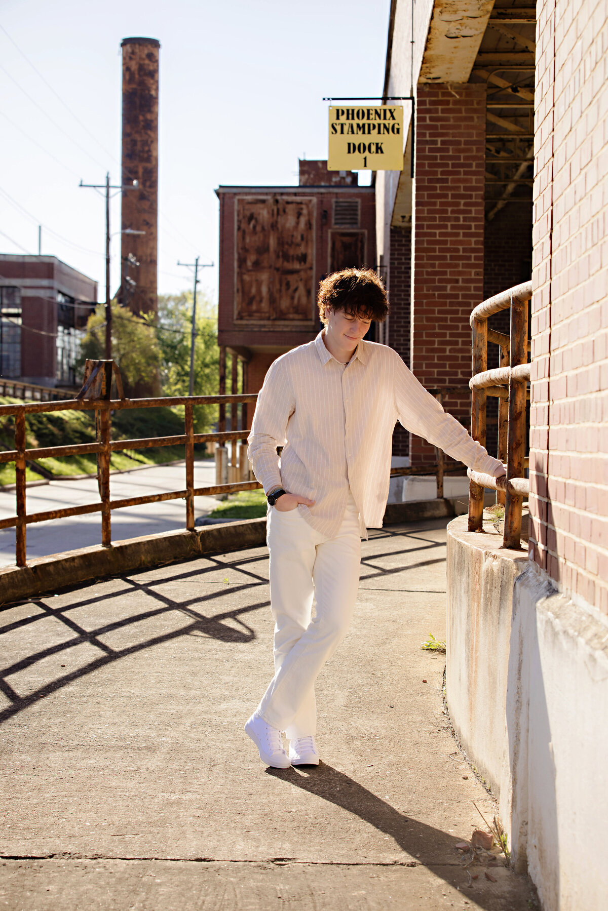 Spring portrait of high school senior in vintage outfit, seated in an urban setting at Camp North End by Charlotte senior photographer.