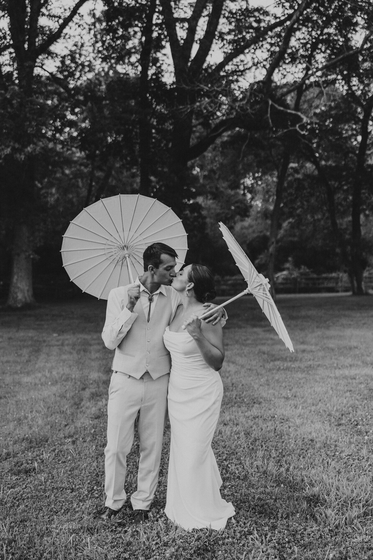 Bride and groom holding parasols at their wedding – photo by Mallory’s Gallery.