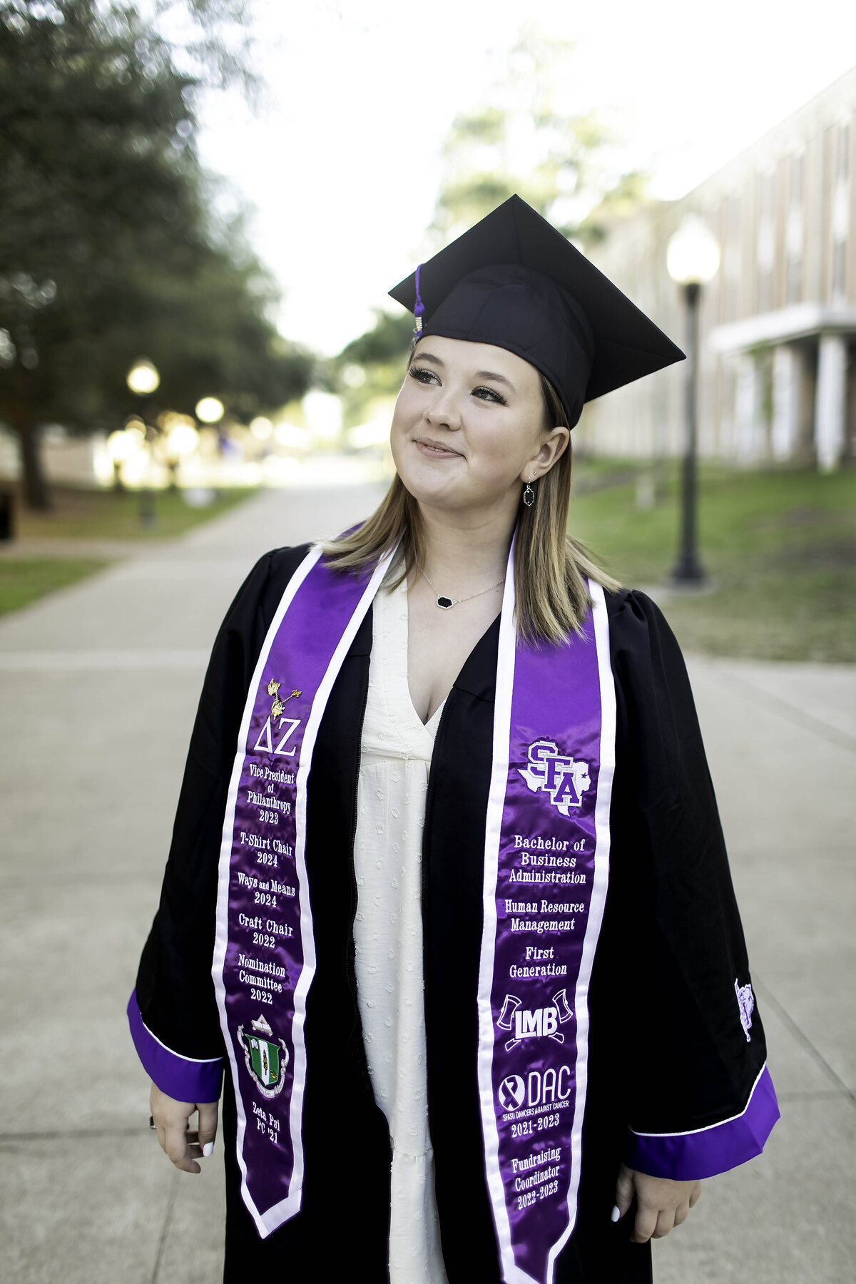 A high school senior smiles confidently in their photoshoot, dressed in a casual outfit