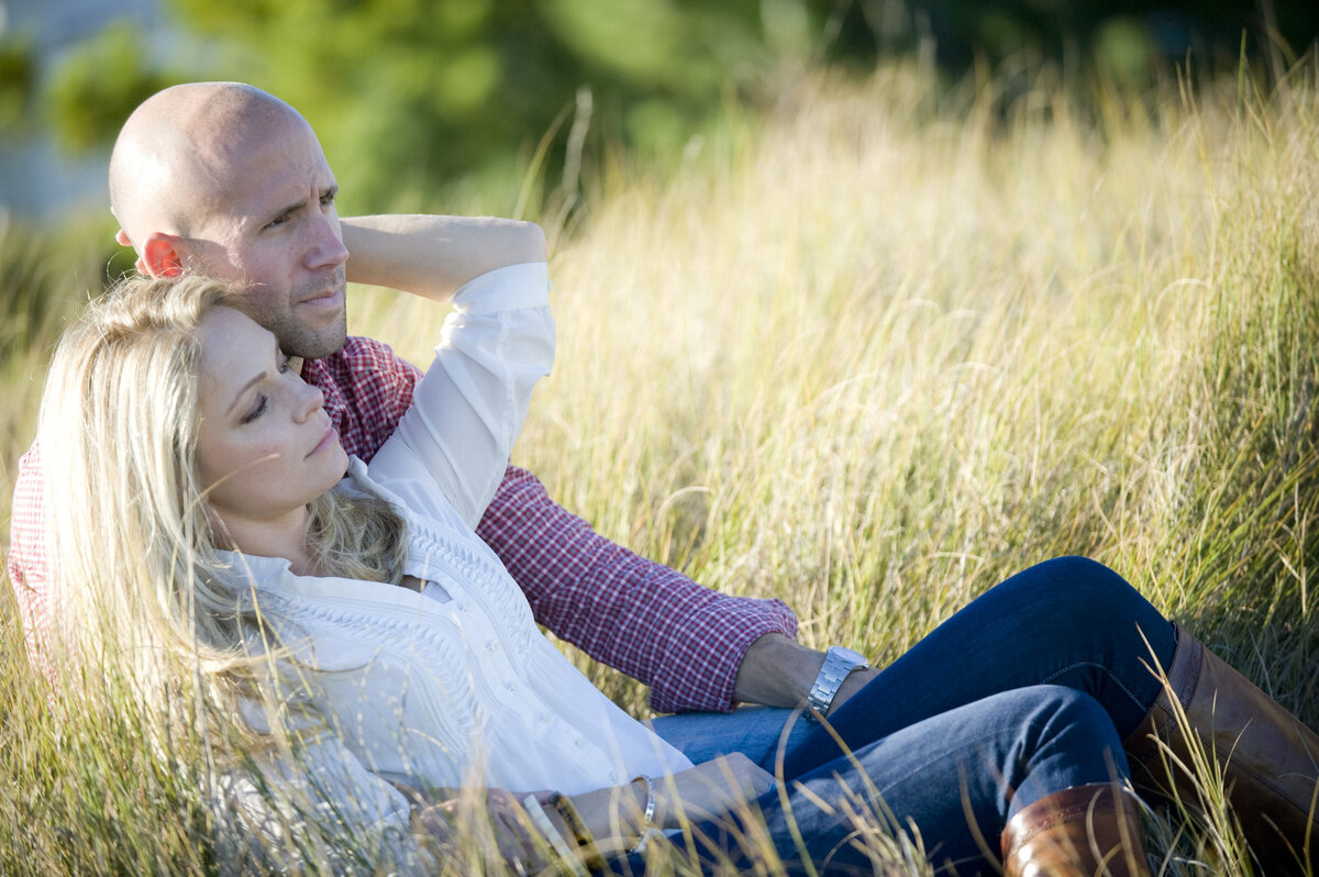 A couple laying together in tall grass 