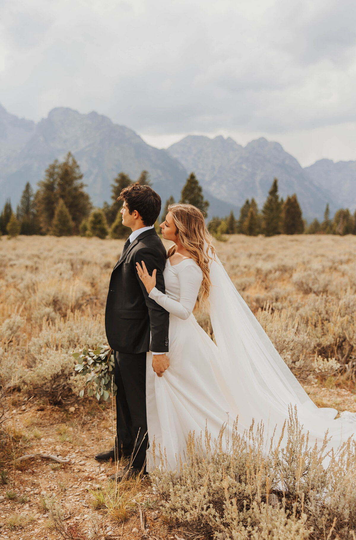 bride and groom posing in front of mountains