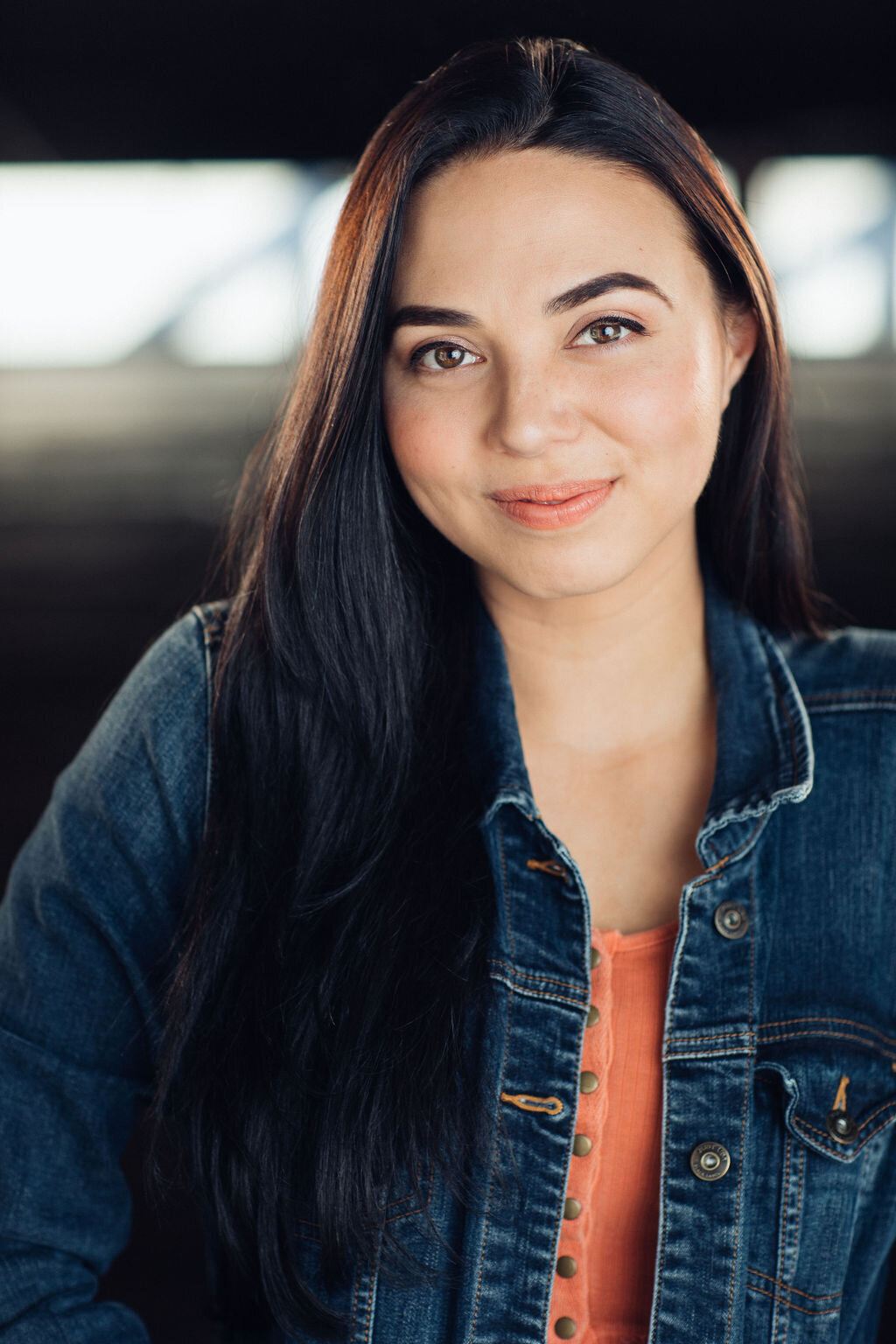 Headshot Photograph Of Young Woman In Outer Dark Blue Denim Jacket And Inner Orange Buttoned Blouse Los Angeles