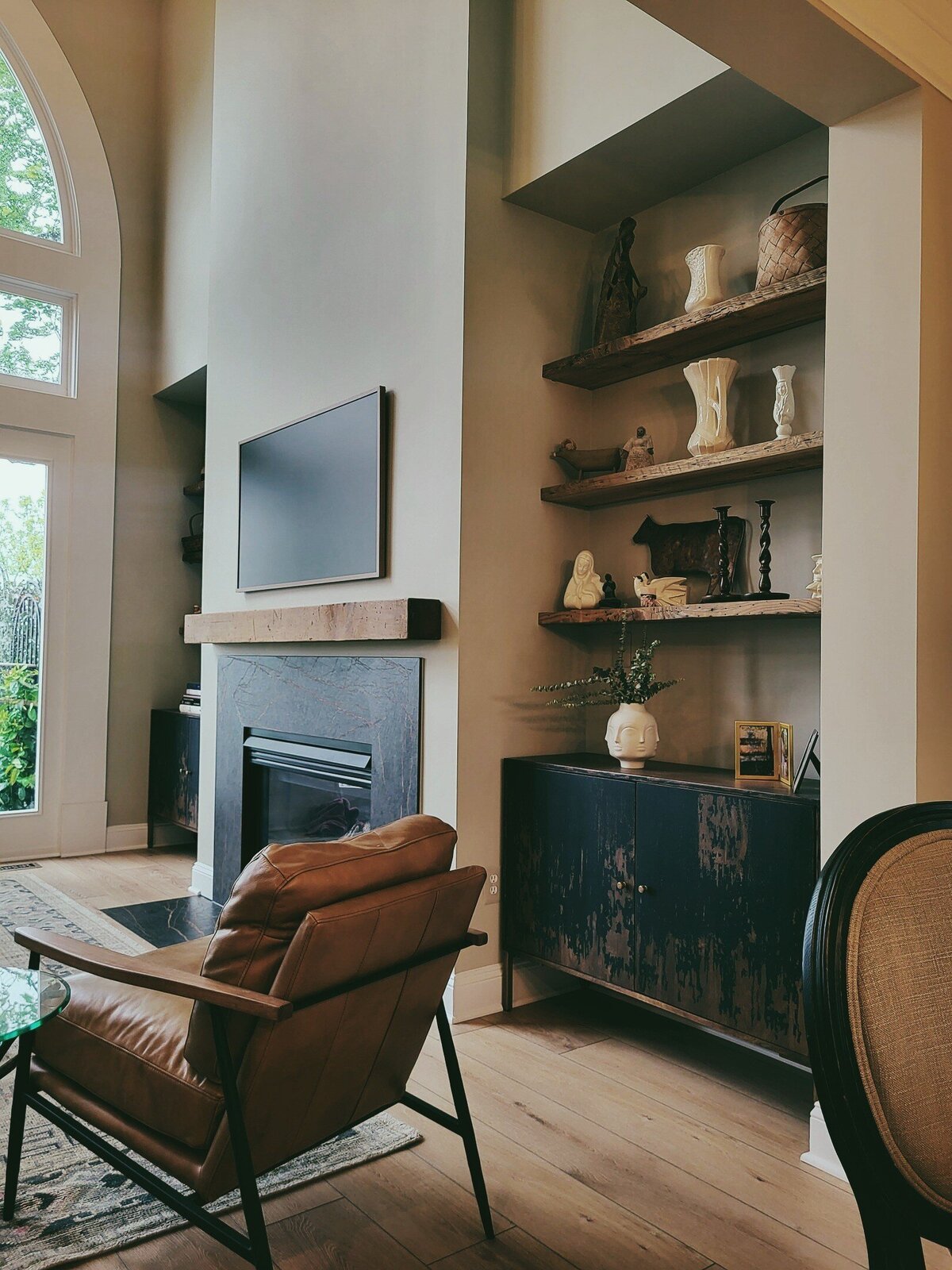 Fireplace with antique wood mantle and antique wood bookshelves in the nooks beside the fireplace with artisticaly painted black and tan cabinets
