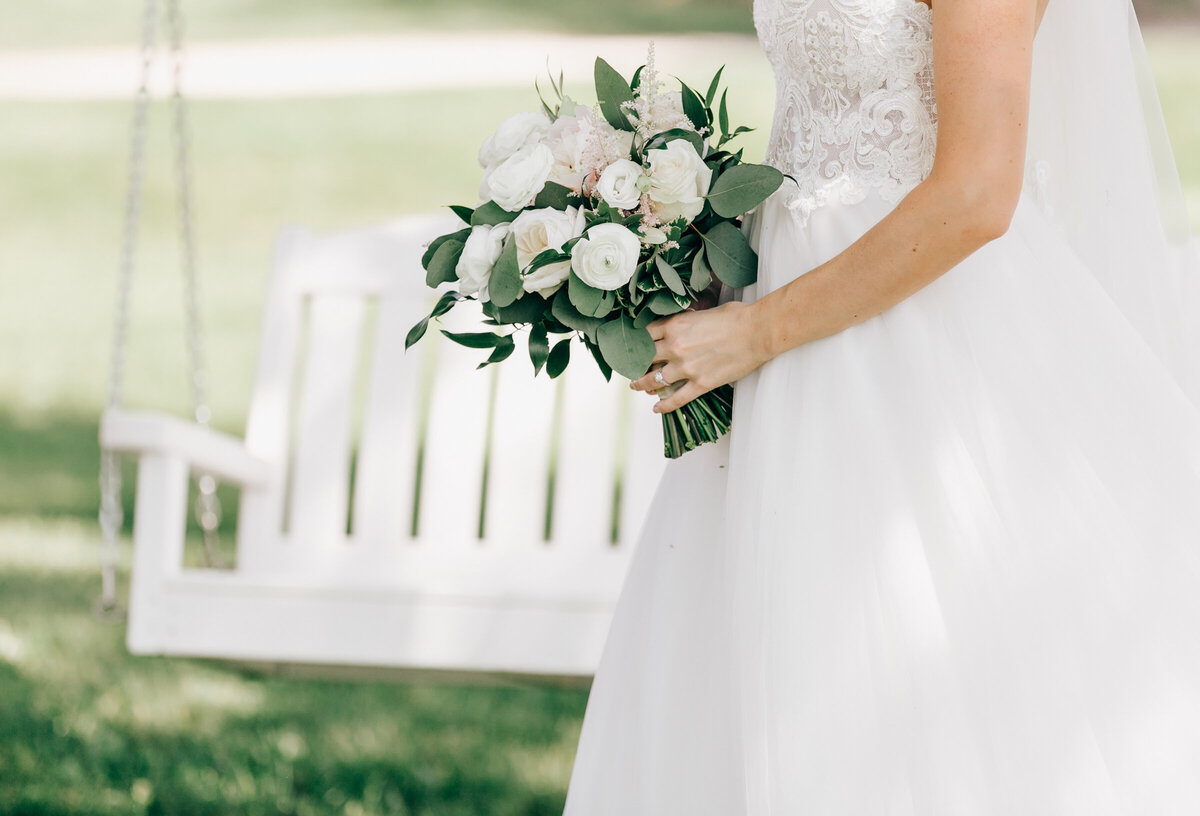 Bride holding glamorous bouquet of white roses and eucalyptus during glamorous outdoor wedding portraits by Nova Markina Photography