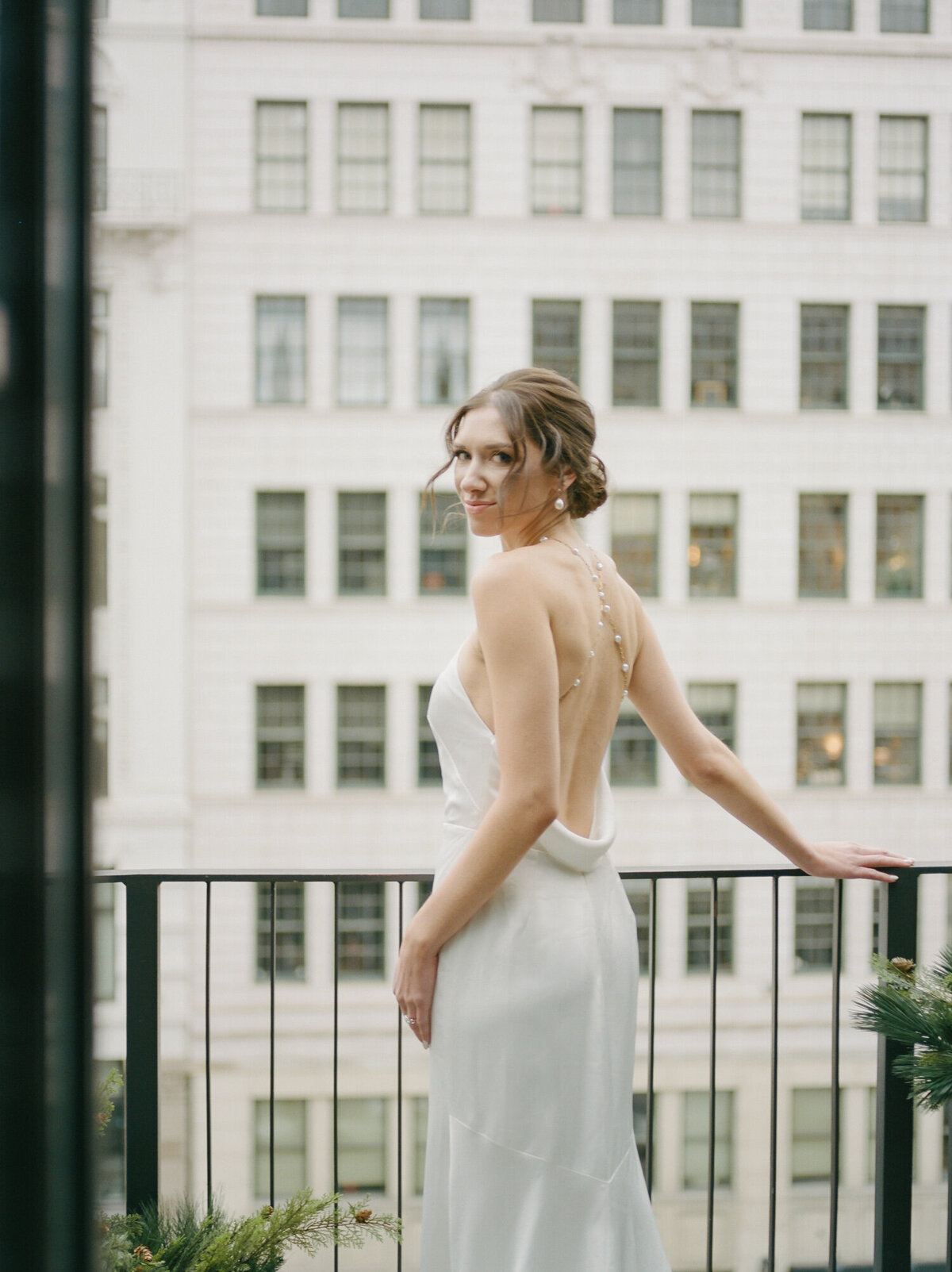 Bride in backless pearl wedding dress on balcony at Shinola Hotel, Detroit captured by Detroit film wedding photographer Christina Harrison