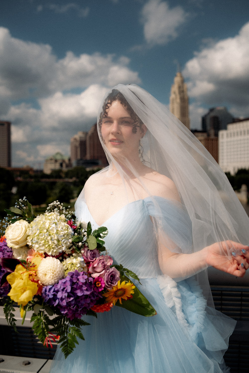 90s aesthetic with blue wedding dress and colorful flower with veil on over brides face