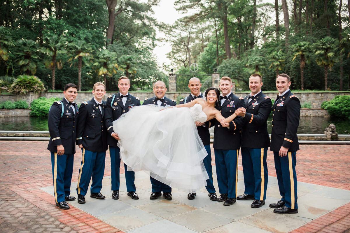 Groomsmen in uniform holding up the bride at the Norfolk Botanical Gardens