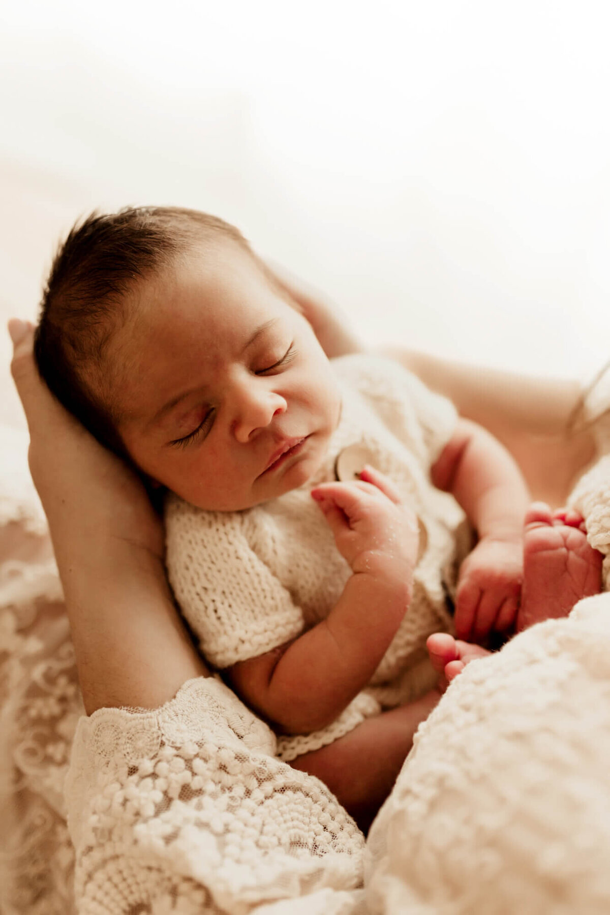 Baby boy sleeps in his mother's arms.