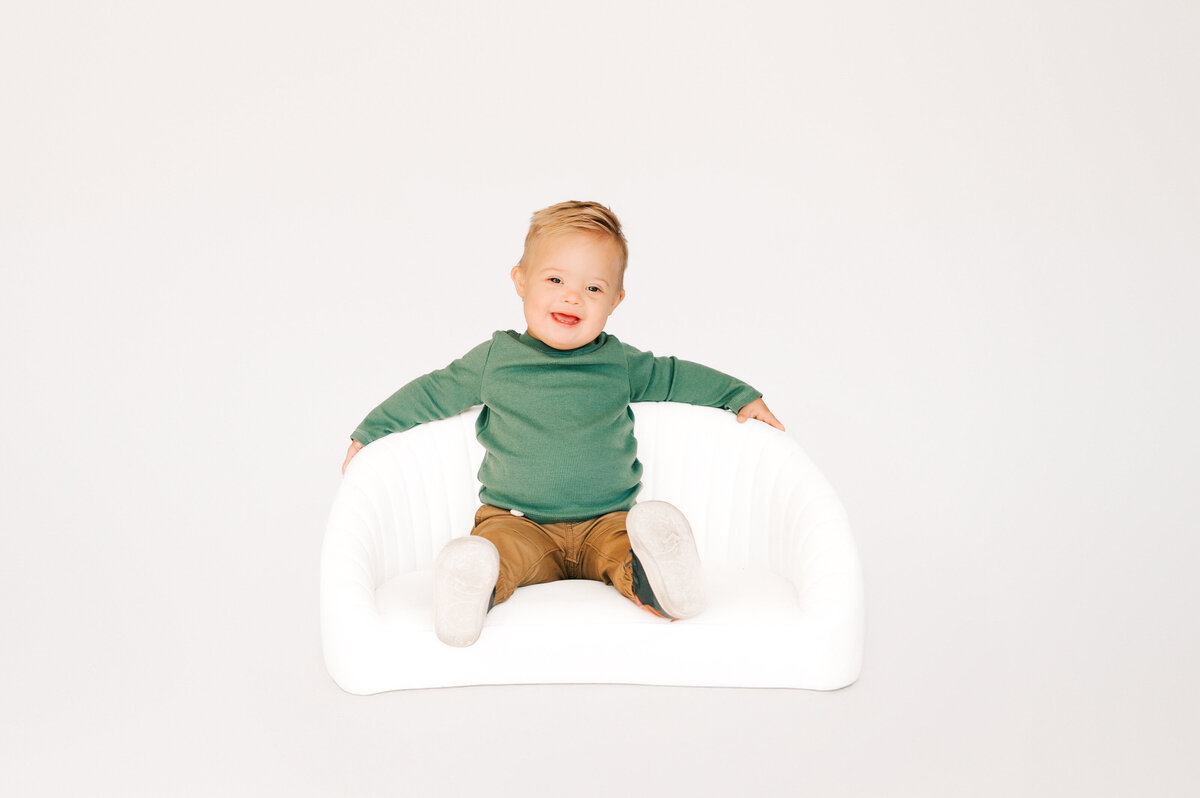 Springfield MO kids photographer captures down syndrome boy sitting on couch during 1st birthday milestone photography session