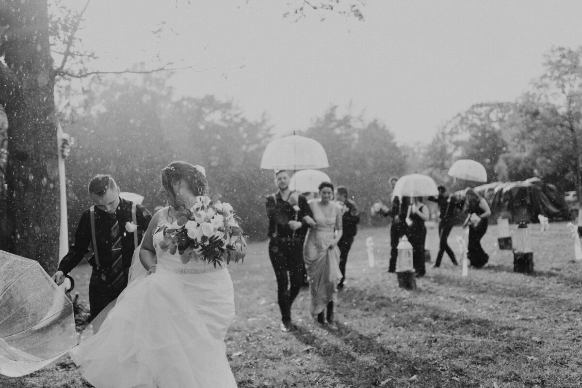 Group walking in the rain with umbrellas for wedding in st louis missouri