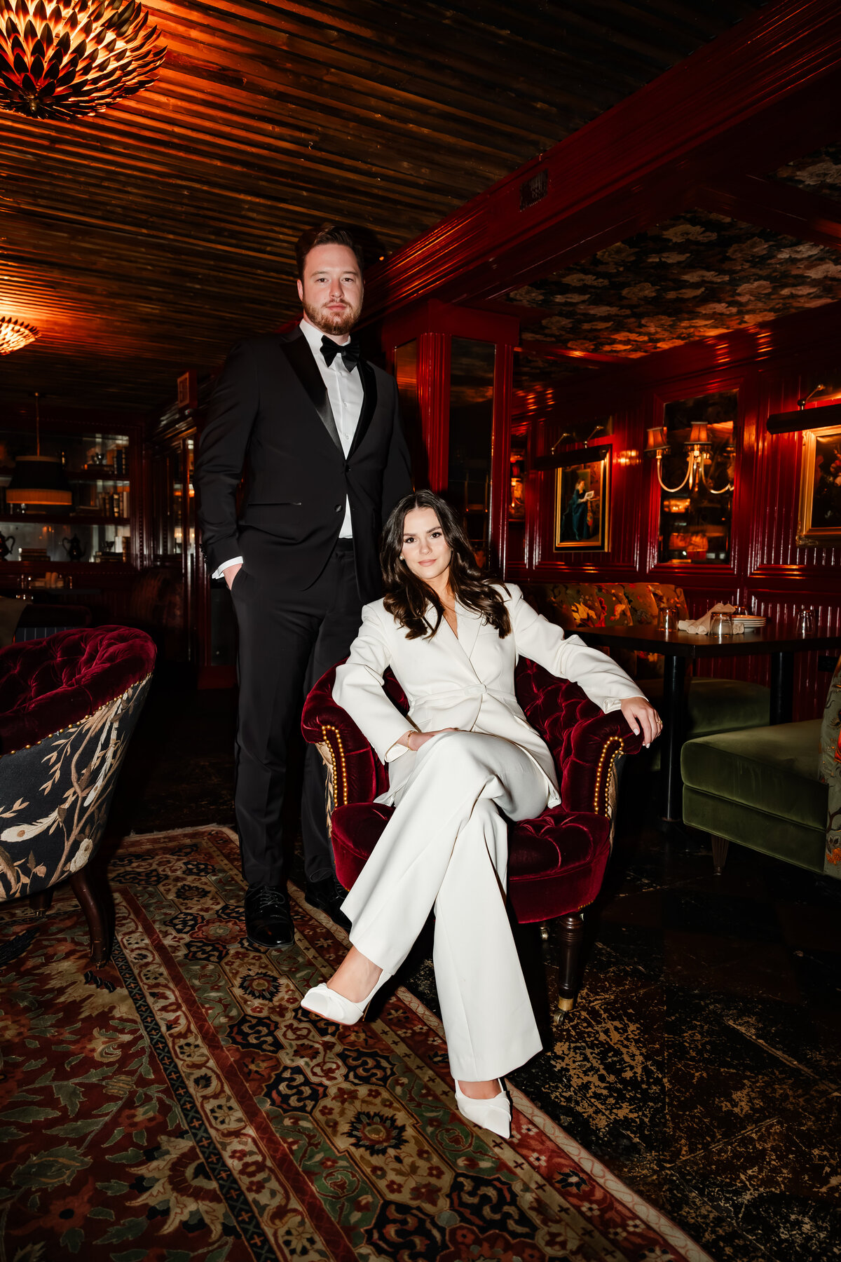 A man in a tux and a women in white suite sit inside Gilt Bar in Chicago.