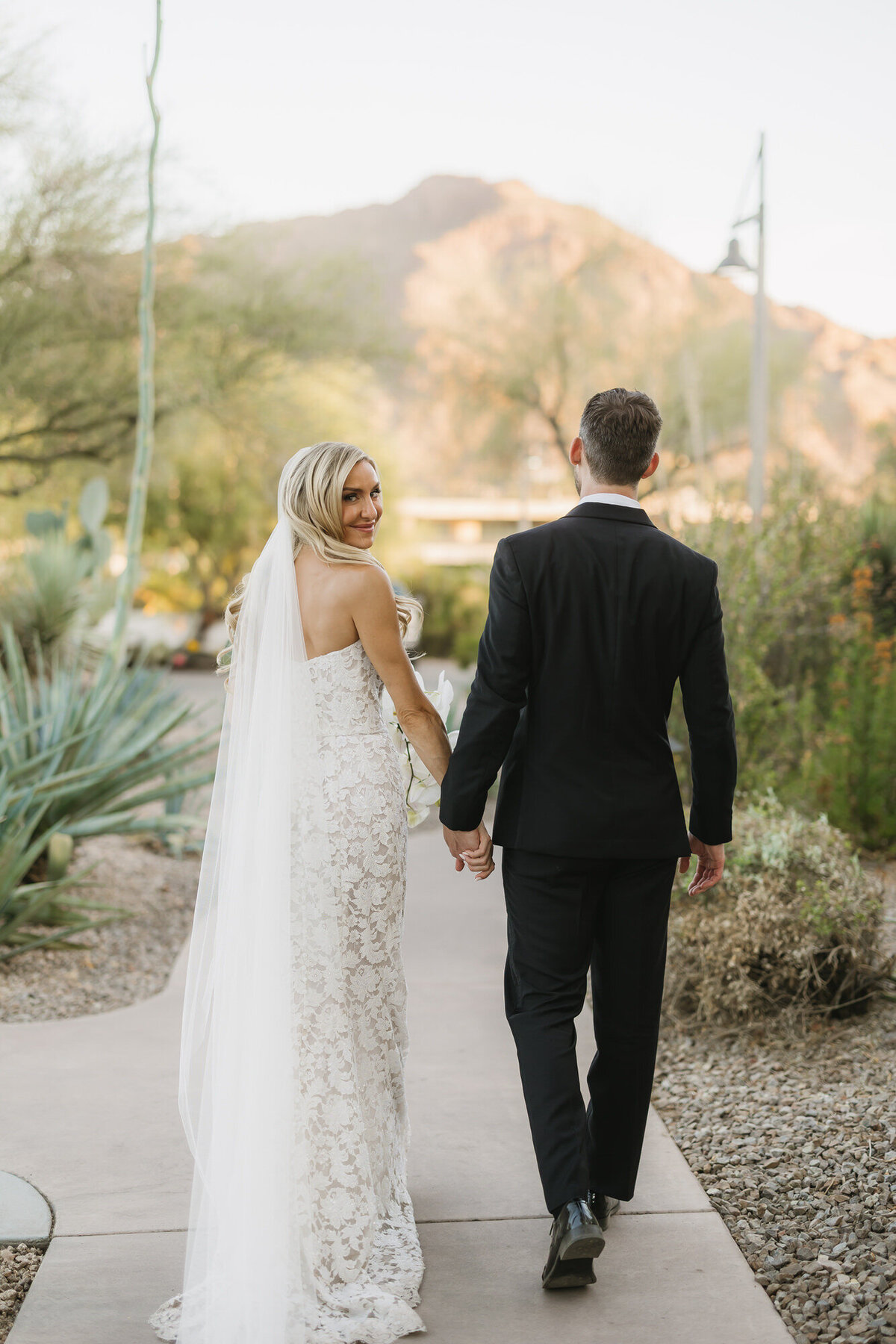 Bride looking over shoulder while walking with groom